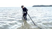 Jennifer Ruesink uses experimental concrete vibrator while standing in water
