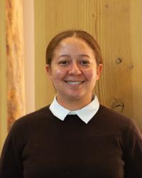A profile photo of Andrea Durant, who is wearing a brown sweater and standing in front of wood panels.