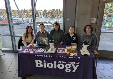 5 biology students sitting at a table at an event