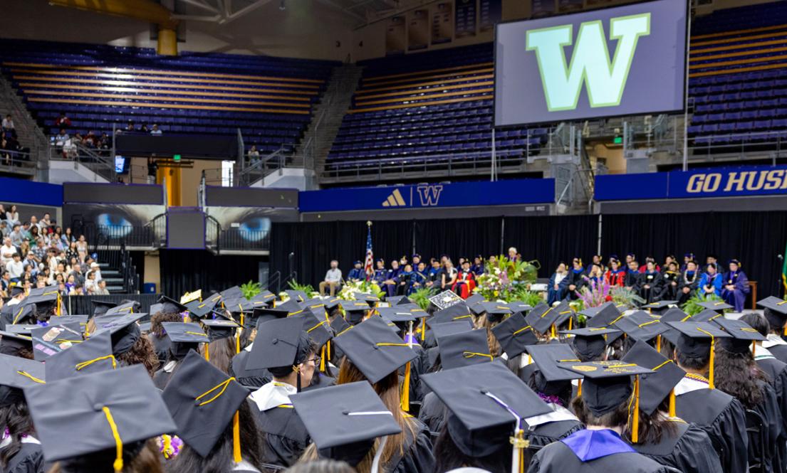 Graduates in caps and gowns seated in an arena during Biology 2025 graduation ceremony