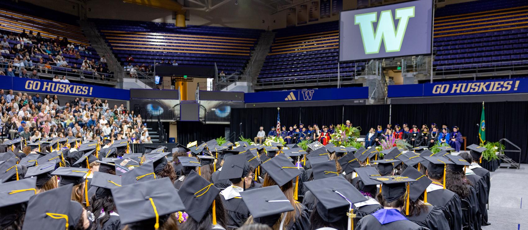 Graduates in caps and gowns seated in an arena during Biology 2025 graduation ceremony