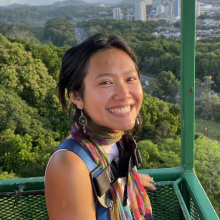 Melanie smiling on a canopy crane with forest and Panama City in the background